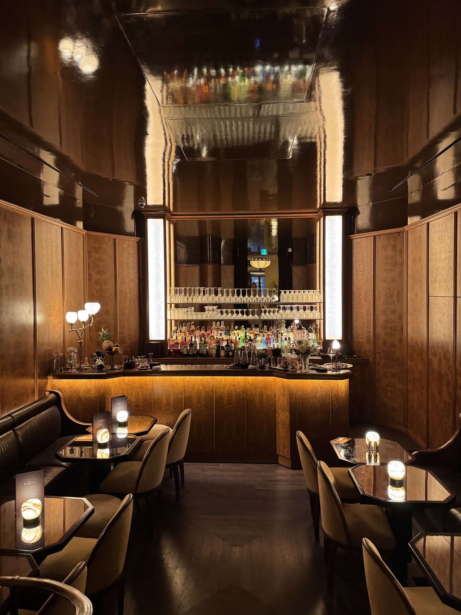 Warm walnut cocktail bar with backlit glass shelving