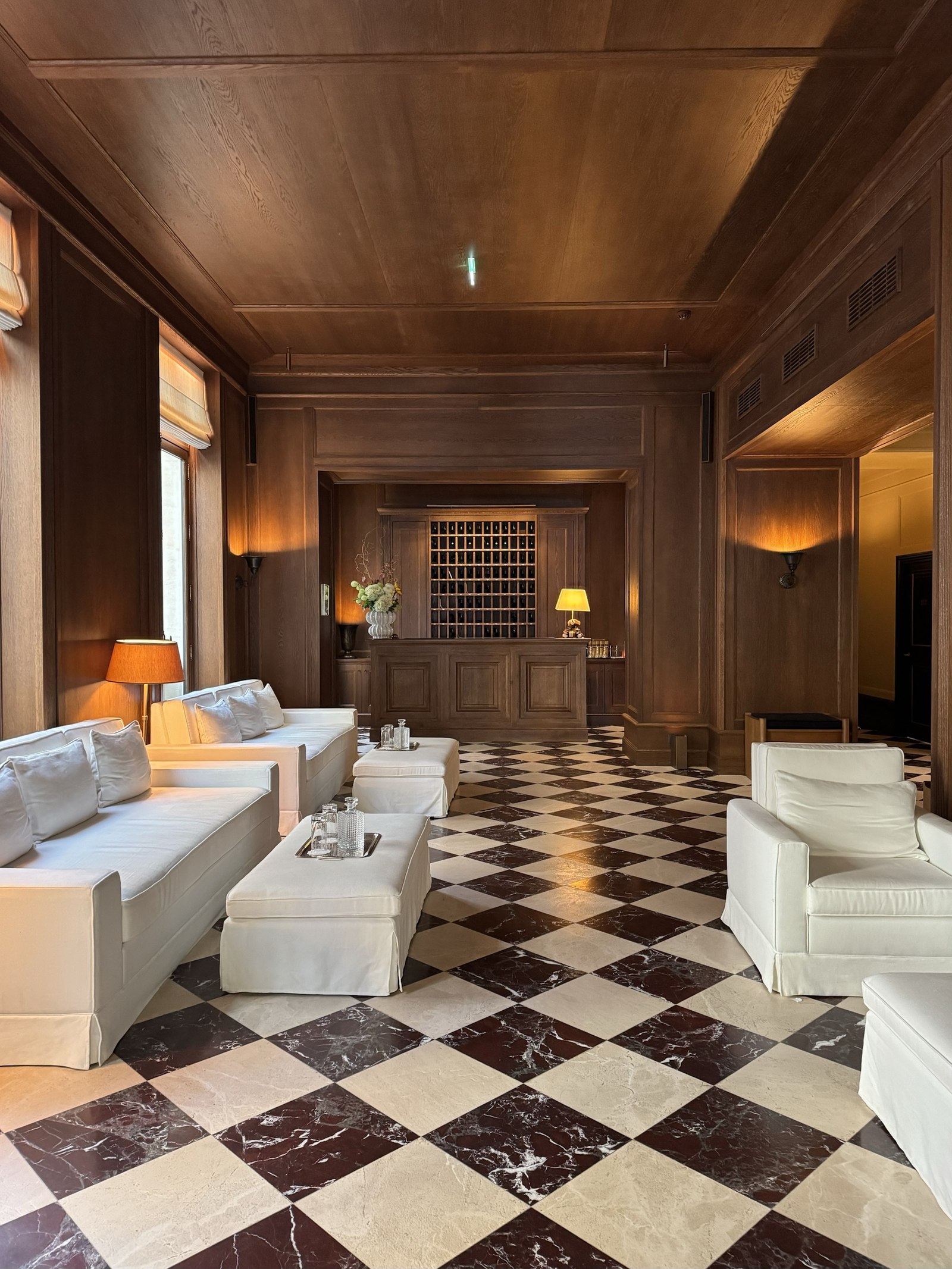 Wood-paneled hotel lobby with black-and-white checkerboard marble floor